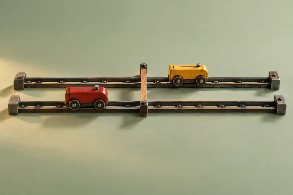 Editorial illustration: Yellow and red carriages occupy different positions on parallel tracks with a shared crosspiece.