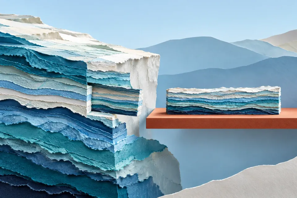 Editorial illustration: A section of thin blue and white paper layers rests on a terracotta shelf beside a layered paper cliff.